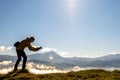 Silhouette of a backpacker photographer taking pictures of morning landscape in autumn mountains with digital camera Royalty Free Stock Photo