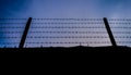 Silhouette barbed wire fence on the wall with twilight blue sky background Royalty Free Stock Photo