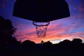 Silhouette of a basketball hoop against a colorful cloudy sky at a sunset Royalty Free Stock Photo