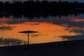 Silhouette of beach sunshade on beach of the Dnieper river at sunset