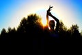 Silhouette of a beautiful dancing woman and hands at sunset on a background of trees