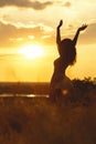 Silhouette of a beautiful girl dancind and spinning in a dress at sunset in a field, happy young woman enjoying nature Royalty Free Stock Photo