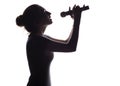 Silhouette of beautiful girl singing into microphone, profile of young woman face performing lyric song on white isolated Royalty Free Stock Photo