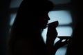 Silhouette of a girl near a window with a cup of hot drink Royalty Free Stock Photo