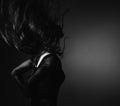 Silhouette of beautiful girl with sporty slim figure in black dress moving with hair above the head on dark shadow art background Royalty Free Stock Photo