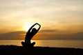 Silhouette of beautiful woman sitting cross legged and stretching her arms up to sky, sunrise on the horizon in background Royalty Free Stock Photo