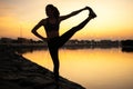 Silhouette of a beautiful yoga woman doing balance exercise at sunrise or sunset near the sea coast. Royalty Free Stock Photo