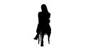 Silhouette Beautiful young woman, girl, model blonde with long hair sitting on a chair and looking to camera.