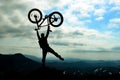 Silhouette bicyclist celebrates on mountaintop