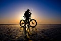 Silhouette of bicyclist standing on the clear ice