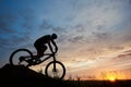 Silhouette of bicyclist wearing helmet and sportswear on mountain bike coming down the hill at sunset Royalty Free Stock Photo