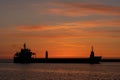 Silhouette of a big container ship at sunrise and exit from a Royalty Free Stock Photo