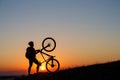 Silhouette of a bike tourist on mountain peak.