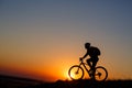 Silhouette of a bike tourist on mountain peak.