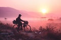 silhouette of a bike traveler riding a bicycle across a field at a foggy pink dawn Royalty Free Stock Photo