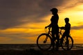 Silhouette biker lovely family at sunset over the ocean. Mom and daughter bicycling at the beach. Royalty Free Stock Photo