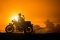 Silhouette of biker man sitting smokes with his motorbike beside the natural lake and beautiful, enjoying freedom and active lifes