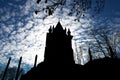 Silhouette of a black castle and trees against a blue sky with clouds