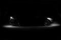 Silhouette of black sports car with headlights on black background