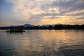 A silhouette boat and man sailing on the calm sea at sunset in the background of mountains and sun beams. Royalty Free Stock Photo