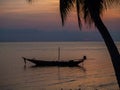 Silhouette of a boat and palm trees against the setting sun with clouds Royalty Free Stock Photo