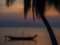 Silhouette of a boat and palm trees against the setting sun with clouds Royalty Free Stock Photo