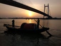 Silhouette of boat sailing over river ganga at dusk with vidyasagar bridge in the background during sunset Royalty Free Stock Photo