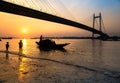 Silhouette boat at sunset on river Hooghly with Vidyasagar setu bridge at the backdrop.