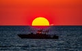 Silhouette of a boat swimming in the ocean with a vibrant sunset in Palm Jumeirah