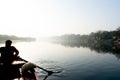 silhouette of boatsman rowing out into the yamuna ganga river in the morning