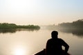 silhouette of boatsman rowing out into the yamuna ganga river in the morning