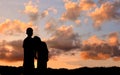 Silhouette of boy and girl stand hand in hand to watch the sunset Royalty Free Stock Photo