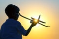Silhouette of a boy lets a model plane fly into the sky against the backdrop of the setting sun. Children`s dream of a future Royalty Free Stock Photo