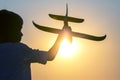 Silhouette of a boy lets a model plane fly into the sky against the backdrop of the setting sun. Children`s dream of a future Royalty Free Stock Photo