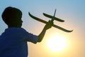 Silhouette of a boy lets a model plane fly into the sky against the backdrop of the setting sun. Children`s dream of a future Royalty Free Stock Photo