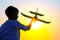 silhouette of a boy lets a model plane fly into the sky against the backdrop of the setting sun. Royalty Free Stock Photo