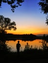Silhouette of a boy looking at the sunset or sunrise on the river or lake beach. Vertical composition with copyspace for your text Royalty Free Stock Photo