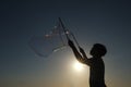 Silhouette boy playing with a bubble wand on the beach Royalty Free Stock Photo