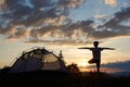 Silhouette of boy practice yoga on top of mountain at dawn near campsite under sky with clouds and bright morning sun Royalty Free Stock Photo