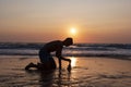 Silhouette of a boy teenager builds a zen pyramid of pebbles on the Adriatic sea shore or beach at sunset