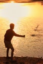 Silhouette of a boy throwing stones in a water, Khichan village, India Royalty Free Stock Photo