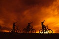 Silhouette boys riding bicycle at sunset or sunrise