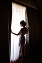 Silhouette of bride girl in the morning in full growth near window in dressing gown on wedding day Royalty Free Stock Photo