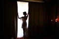 Silhouette of bride girl in the morning in full growth near window in dressing gown on wedding day Royalty Free Stock Photo