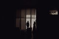 Silhouette Of The Bride and Groom Standing At The Window Of Their Wedding Day.Side view of silhouettes couple in love looking at