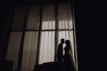 Silhouette Of The Bride and Groom Standing At The Window Of Their Wedding Day.Side view of silhouettes couple in love looking at