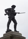 Silhouette of a bronze British Tommy statue with drawn bayonet on a UK war memorial