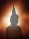 Silhouette Buddha image over brown light sunset backgro