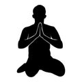 Silhouette of a buddhist man sitting on her knees praying