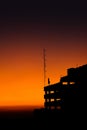 the silhouette of a building against a bright yellow orange sky as a background, a sunset view. Royalty Free Stock Photo